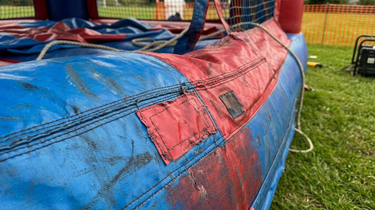 Close-up inspection of used commercial bounce house PVC material and seams